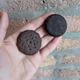 Two chocolate-coated cookies held in palm of hand; left cookie is more textured and lighter in color brown